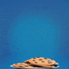 gif of Cookie Monster on a blue background, in front of a plate of chocolate chip cookies. He smiles and looks ready to eat.