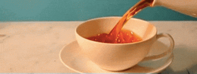 Video gif. A teacup on a saucer is filled with tea in slow motion.