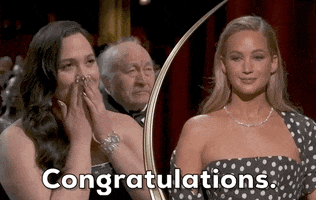 Oscars 2024 GIF. Jennifer Lawrence says, "Congratulations" to Lily Gladstone, who responds by blowing Lawrence a kiss and softly clapping.