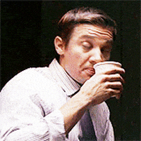 Celebrity gif. Jeremy Renner sips from a cup of coffee and looks over his shoulder, nodding approvingly.
