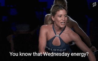 Video gif. Kendall Toole wears a Peloton halter top as she cycles and speaks into a headset microphone saying, "You know that Wednesday energy."