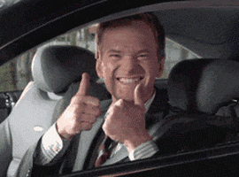 Celebrity gif. Neil Patrick Harris sits in the driver seat of a car and looks at us through his rolled down window. His smile is so wide that he squints his eyes, and he holds up two big thumbs up.