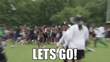Video gif. A large group of hyped up people rush together as a young man looks at us and excitedly yells. Text, "Lets go!"