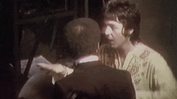 Celebrity gif. A young Paul McCartney of the Beatles emphatically raises his hands over his head for emphasis and exclaims "Boom!"