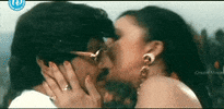 Video gif. Woman sweetly cradles a man's face and kisses him on his forehead, cheek, and chin.