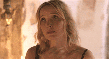 Video gif. Woman looks up towards the sky, crosses her heart, and then prays.