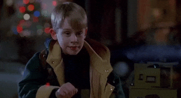 Movie gif. Macaulay Culkin as Kevin in Home Alone Two Lost in New York, smiles smugly as he looks ahead and waves. 