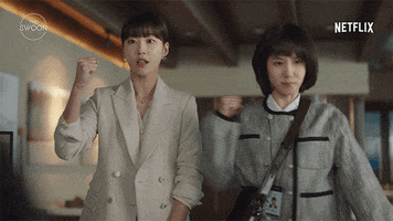 TV gif. Park Eun-bin as Young-woo and Ha Yoon-kyung as Su-yeon in Extraordinary Attorney Woo. Both of them are in the office reporting to a higher up and each of them pump a fist out in cheer and encouragement.