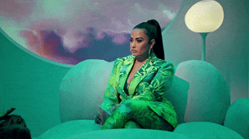 TV gif. Wearing a green suit, Demi Lovato sits on a couch at the Demi Lovato Show and shakes her head in disappointment.