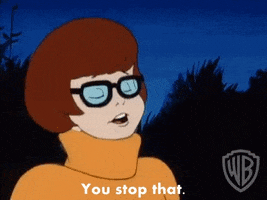 Cartoon gif. Velma from Scooby Doo looks sternly through her thick black glasses. Text, "You stop that."