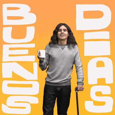 Man standing in front of a yellow background leans toward us and lifts a white mug into the air as he shouts, "Buenos Dias," in Spanish, which appears as text.