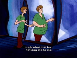 Cartoon gif. Shaggy from Scooby Doo looks at himself in a distorting funhouse mirror. His scraggly body appears thick and heavy set in the mirror. 