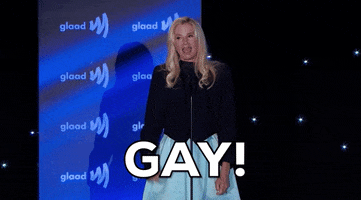 Celebrity gif. Mira Sorvino at 2022 GLAAD Awards raises her fist and shouts "gay!"