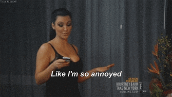 Reality TV gif. Kim Kardashian in Kim and Kourtney Take New York. Kim is looking at her phone and looks peeved. One hand is thrust out and she looks up and says, "Like, I'm so annoyed."