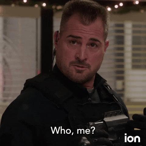TV gif. Character Jack Dalton of ION TV's MacGyver in full police uniform asks "Who, me?"