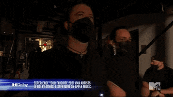 Celebrity gif. Dave Grohl wears a KN95 mask on his face and walks past us. He widens his eyes and glares at us. 